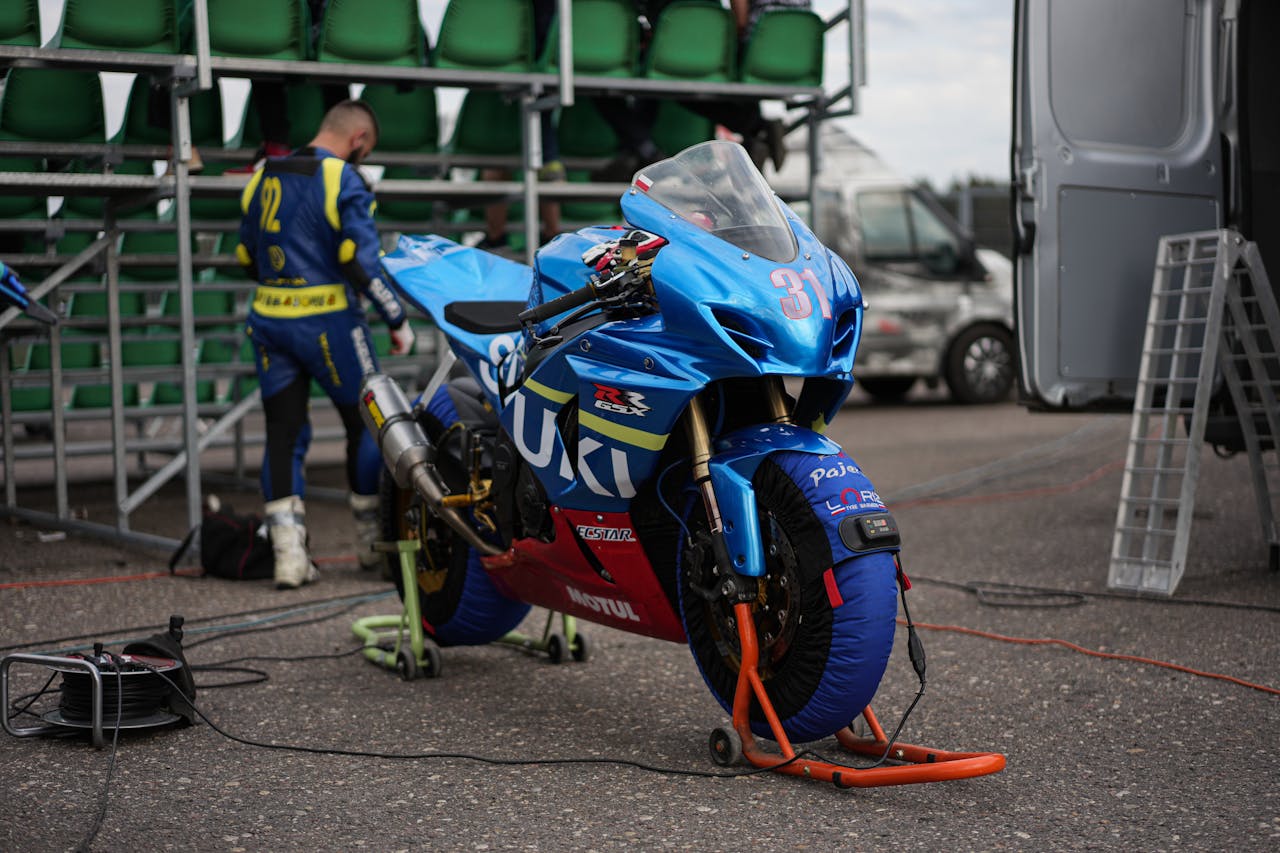 Close-up of a Suzuki motorcycle being prepped by a team for a race.