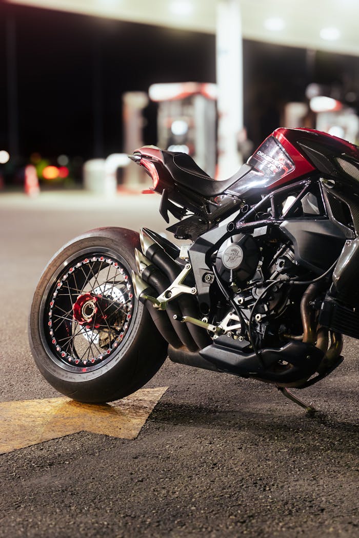 Close-up of a sleek motorcycle parked at a gas station at night, showcasing its intricate mechanical design.