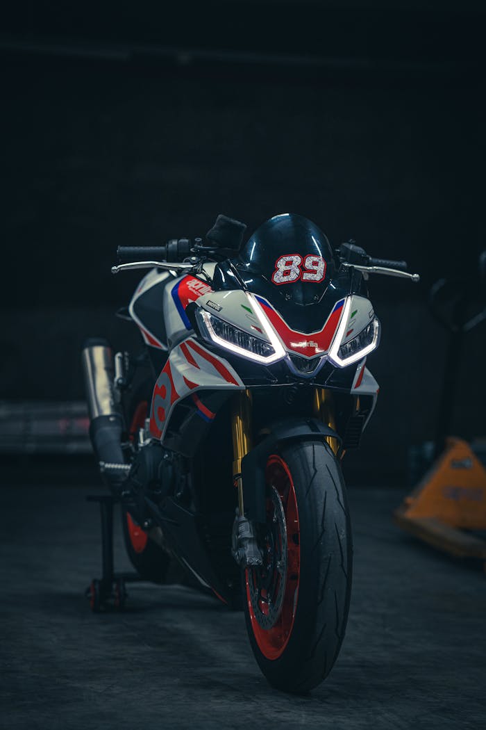 Front view of a sleek high-performance motorcycle with racing graphics parked in a dimly lit garage.