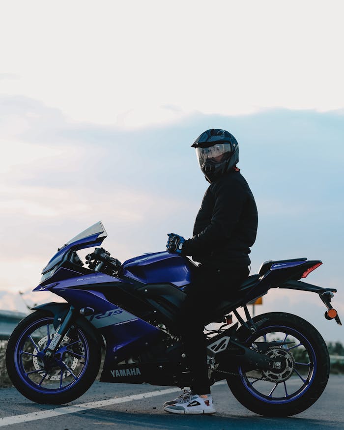 A motorcyclist wearing safety gear rides a Yamaha sport bike on an open road at dusk for an adrenaline adventure.