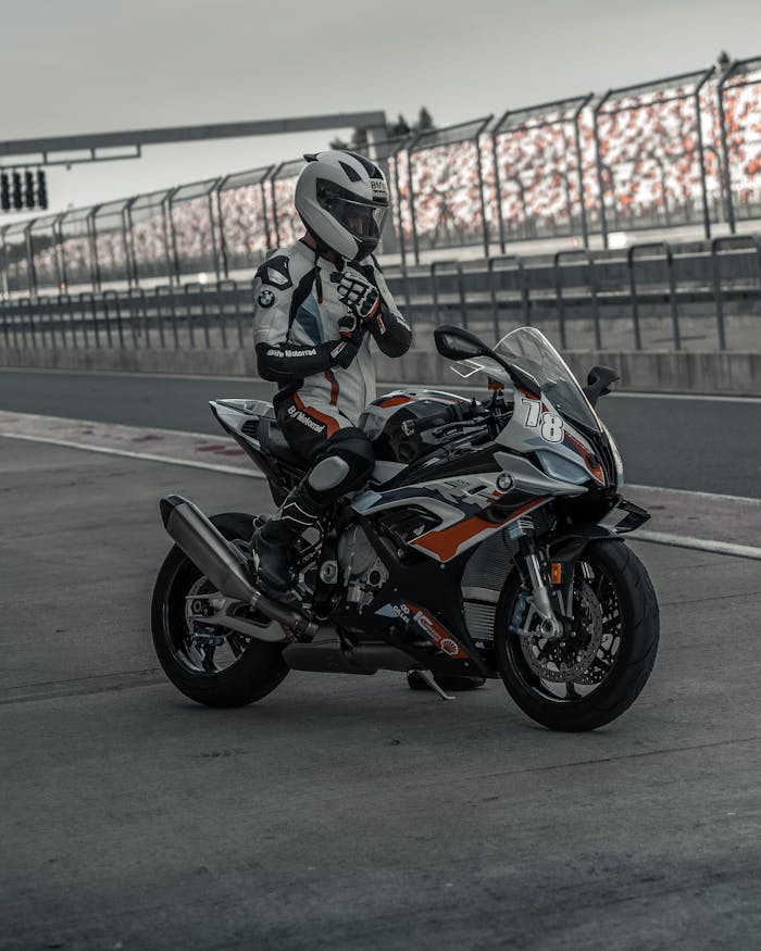 A motorcyclist in racing gear adjusts his helmet on the track.